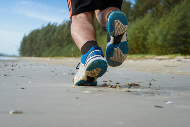 istock Man running on the beach, closeup on shoes 1157981358