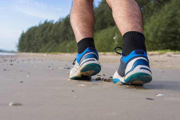 istock Man running on the beach, closeup on shoes 1157981361