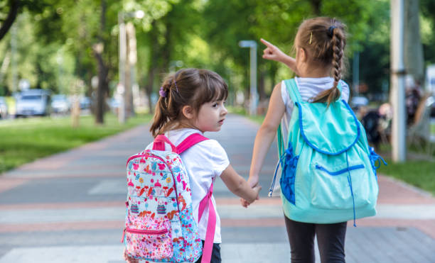 istock Back to school education concept with girl kids, elementary students, carrying backpacks going to class 1157981879