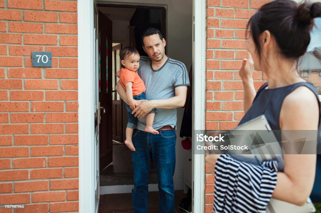 Mum's off to Work A father is standing in the doorway of their home with his son as they say goodbye to the mother who is going to work. Leaving Stock Photo