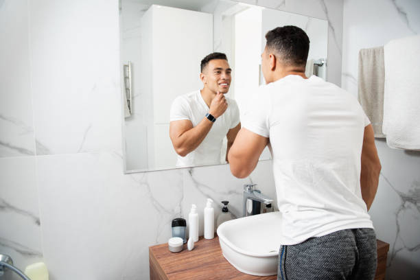 istock Smiling young man touching his chin before mirror 1157982993