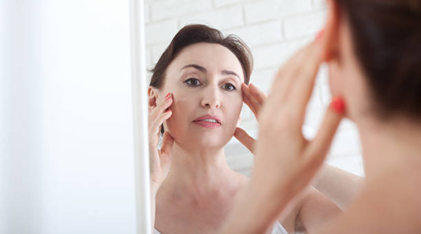Woman looking at wrinkles in mirror. Plastic surgery and collage Woman looking at wrinkles in mirror. Plastic surgery and collagen injections. Makeup. Macro face. Selective focus on the face. Realistic images with their own imperfections. womens issues stock pictures, royalty-free photos & images