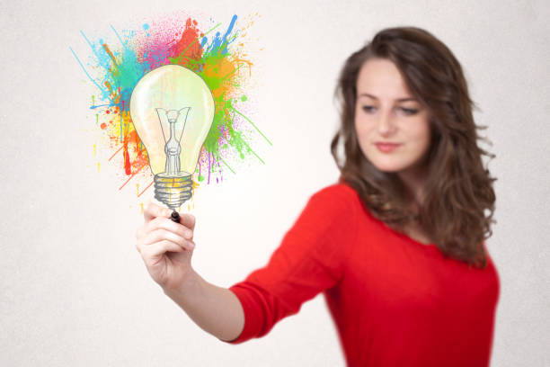 istock Young lady drawing a colorful light bulb with colorful splashes 1157983572
