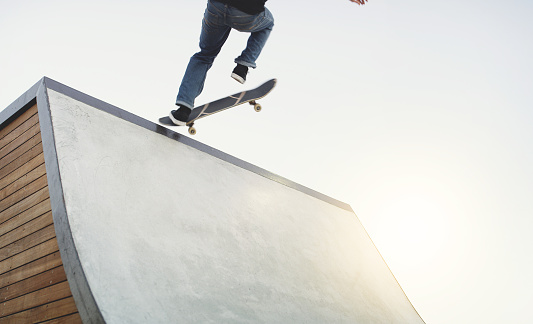 Shot of an unrecognizable man doing tricks on his skateboard at a skate park