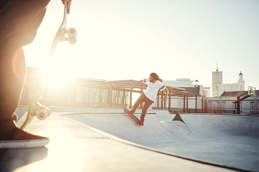 Shot of two young men skating together on their skateboards at a skate park