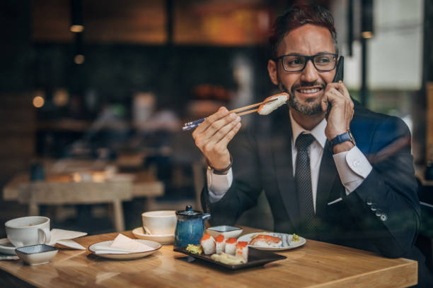 istock Man in the sushi restaurant using phone 1157986875