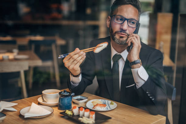 istock Man in the sushi restaurant using phone 1157986930
