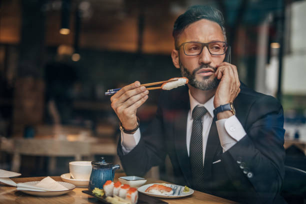 istock Man in the sushi restaurant using phone 1157986949