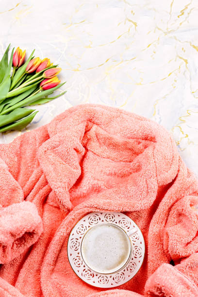 istock Flat lay composition with plush pink bathrobe, coffee, flowers on marble background, top view, copy space 1157989753