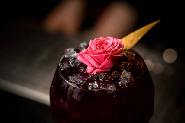 Close-up of alcohol drink decorated with flower and lemon zest
