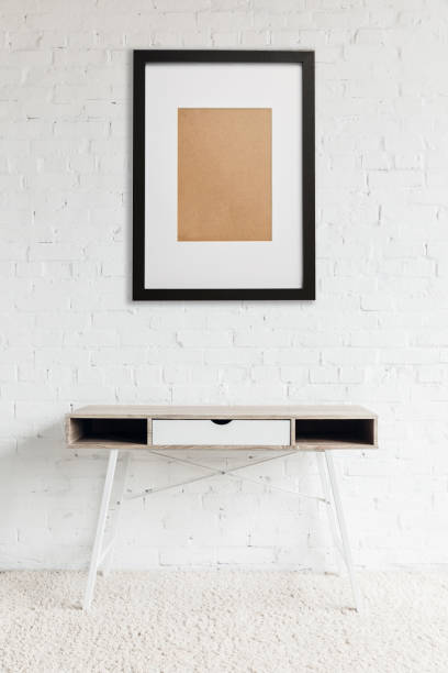 istock modern table standing on carpet near black frame hanging on white brick wall 1157994739