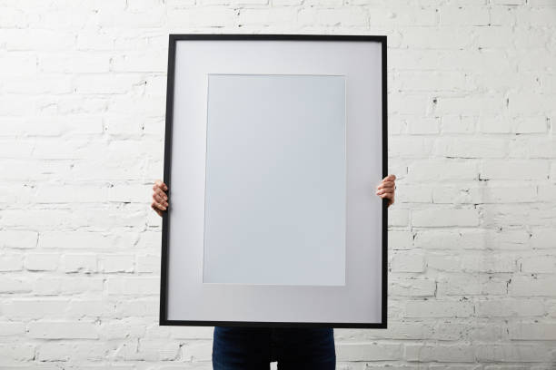 istock woman covering face while holding blank black frame 1157994742