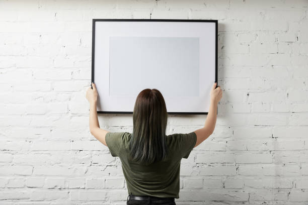 istock back view of woman holding blank black frame in hands 1157994744