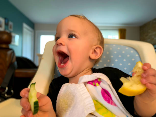 baby jongen eten citroen met zijn handen. - foto’s van jongen stockfoto's en -beelden