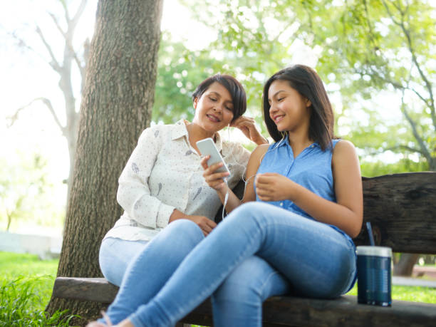 teenage daughter bonding with mother outdoors - parent mother music listening imagens e fotografias de stock