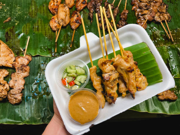 Chicken Satay Appetiser A directly above shot of a unrecognisable person holding a chicken satay with peanut sauce. appetiser stock pictures, royalty-free photos & images