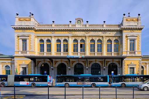 Trieste, Italy, April 17, 2019 : The austro hungarian architecture central train station, with city bus stopped in front to pick up passenger on a blue sky day