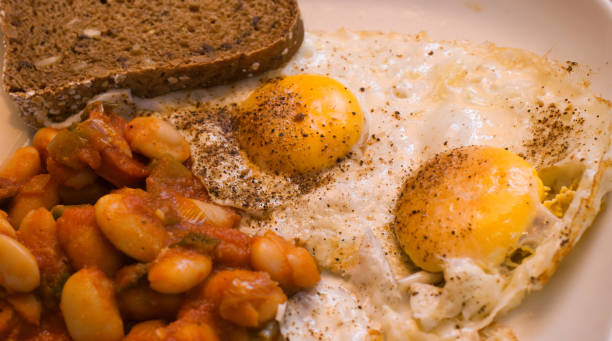 istock Fried egg with bread and baked white beans in tomato sauce, food 1158008529