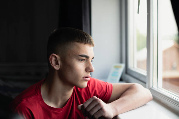 Reminiscing Teenager Emotional, low lighting shot of a teenage boy stressed about exams. only teenage boys stock pictures, royalty-free photos & images