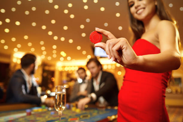 beautiful girl holding a chip in her hand in a casino - smiling casino human hand beautiful imagens e fotografias de stock