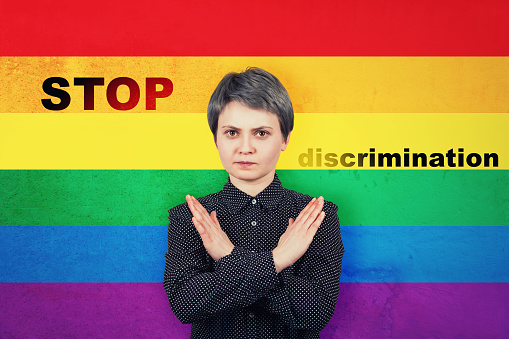 Serious, confident woman holding arms crossed gesturing prohibition, no sign, deny, ban or refusal. Stop discrimination LGBT flag symbol. Equal rights between genders concept. Metaphor of social issue