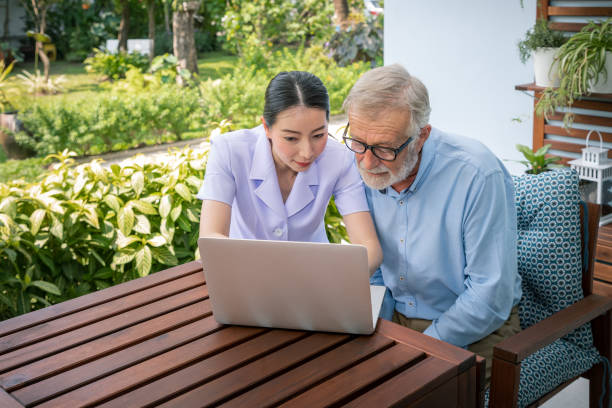 istock Caregiver assist senoir eldery man using notebook laptop computer connect to Internet 1158017487