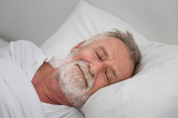 istock Senior elderly man sleeping happily with white blanket in bedroom 1158017527