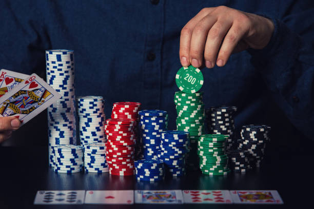 nahaufnahme von jungen mann pokerspieler hände zeigen karten und nehmen chips am casino-tisch. gewinner des glücksspielturniers - table house of cards strategy business stock-fotos und bilder