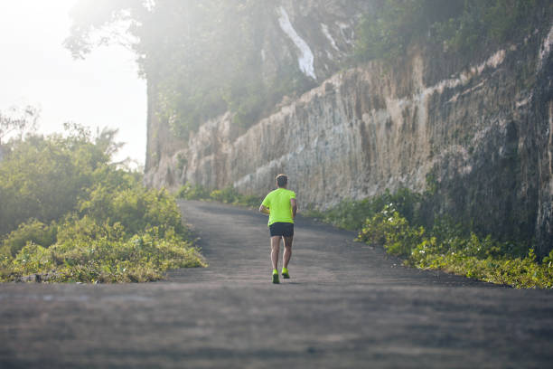 istock Man jogging on a downhill / uphill in suburb mountain road. 1158019062