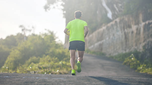 istock Man jogging on a downhill / uphill in suburb mountain road. 1158019157