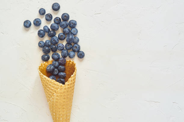 istock Top view of waffle cone with blueberries on white concrete background with copy space 1158019182