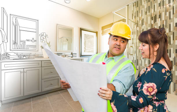 hispanic male contractor talking with female client over blueprint plans in front of bathroom drawing gradating to photo - indoors blueprint smiling built structure stock-fotos und bilder