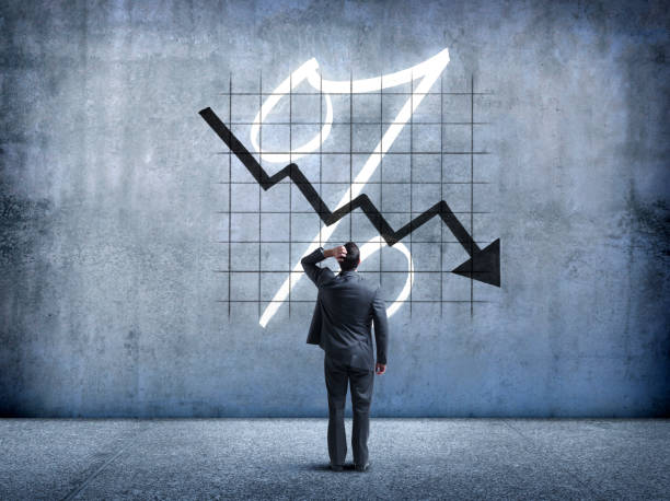 Businessman Looking Up At Falling Interest Rates A businessman places his hand on his head as he looks up and is perplexed by a chart indicating falling interest rates. falling behind stock pictures, royalty-free photos & images
