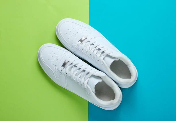 istock Fashionable white sneakers on a two-tone background. Top view 1158027108