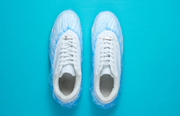 istock White sneakers in boot covers on blue background. Top view. Minimalism 1158030652