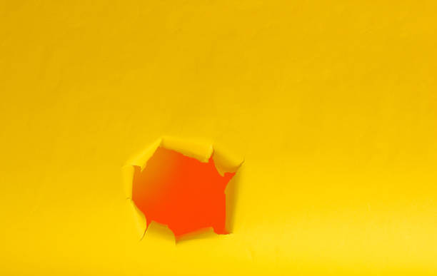 istock Hole of torn yellow paper. Copy space 1158031348