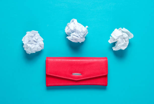 istock Minimal concept. Crumpled paper balls, red leather wallet on blue background 1158032940