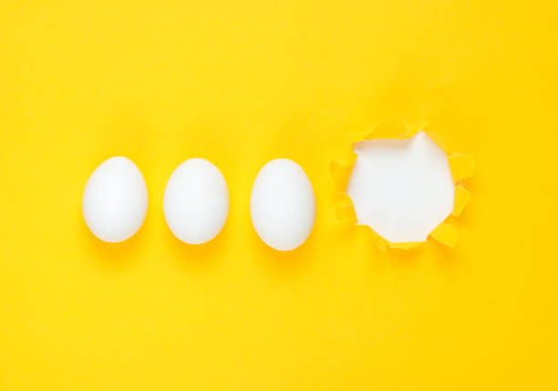 istock White chicken eggs and torn hole yellow paper. Top view, minimalism 1158033303