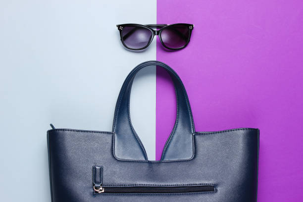 istock Leather bag, sunglasses on gray-purple background. Top view 1158033526