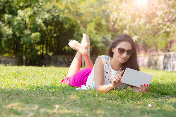 femme utilisant la tablette numérique - women grass glasses e reader photos et images de collection