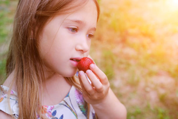 istock Girl eating strawberry 1158037203