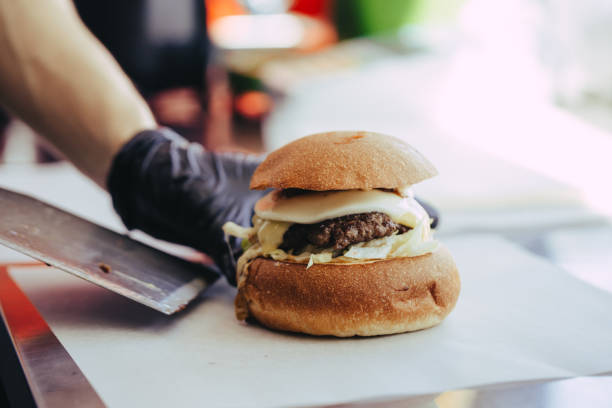 istock Cook preparing burger adding the sauce on the cream cheese. Three burgers. 1158041934