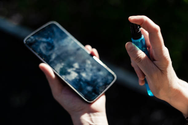 Person’s hands holding and cleaning a mobile phone screen stock photo