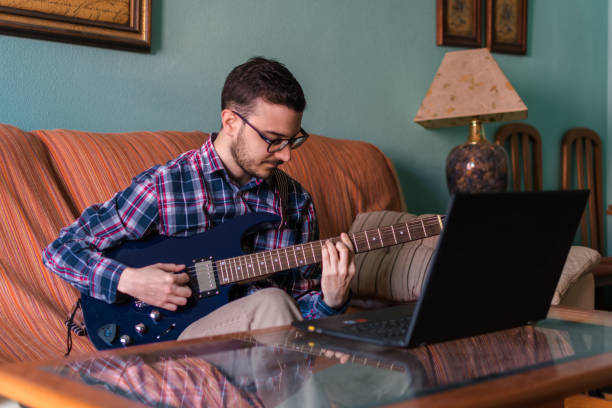 istock Man learn playing electric guitar at home 1158046808