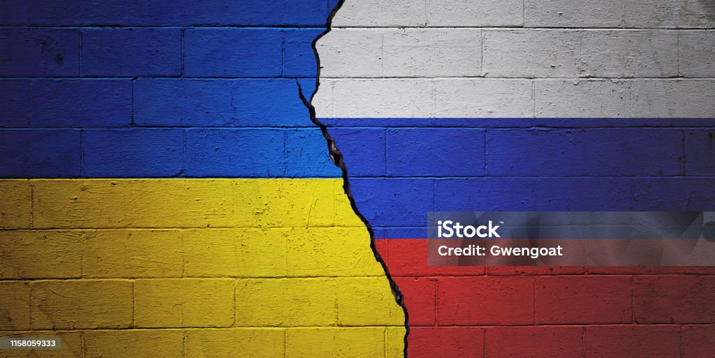 Ukraine vs Russia Cracked brick wall painted with a Ukrainian flag on the left and a Russian flag on the right. Ukraine Stock Photo
