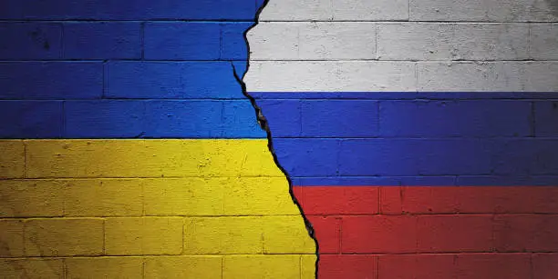 Cracked brick wall painted with a Ukrainian flag on the left and a Russian flag on the right.