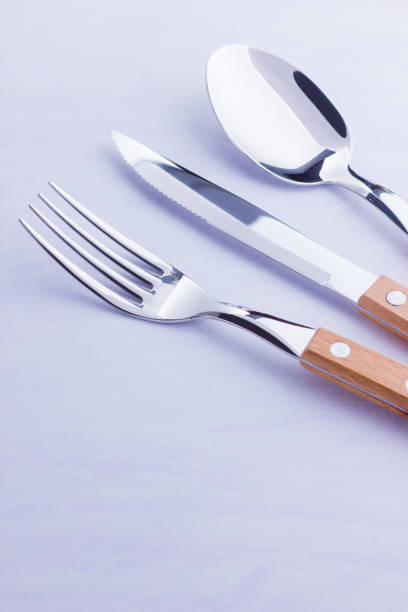 istock Set of cutlery: knife, fork, spoon on white background. Table setting. Concept of cutlery with wooden handles - laconic minimalistic design. Top view 1158060099