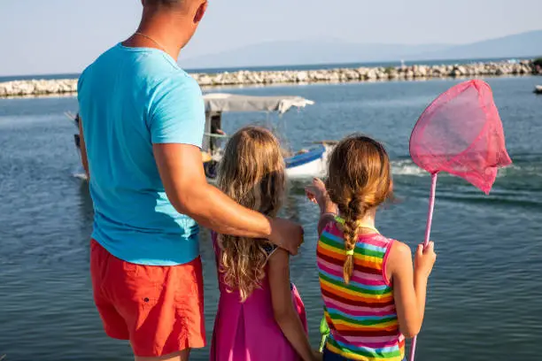 Photo of Father and girls looking to fishing boat