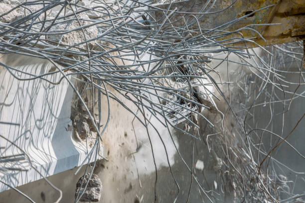 Professional demolition of reinforced concrete structures using industrial hydraulic hammer. Rods of metal fittings. Wreckage and crumbles of concrete.