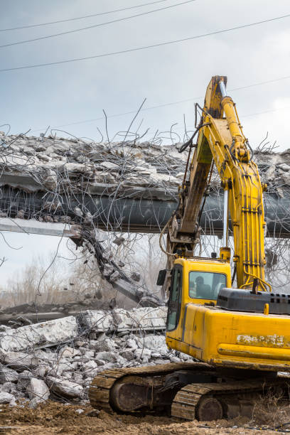 Professional demolition of reinforced concrete structures using industrial hydraulic hammer. Rods of metal fittings. Wreckage and crumbles of concrete. Professional demolition of reinforced concrete structures using industrial hydraulic hammer. Rods of metal fittings. Wreckage and crumbles of concrete. deconstruct stock pictures, royalty-free photos & images